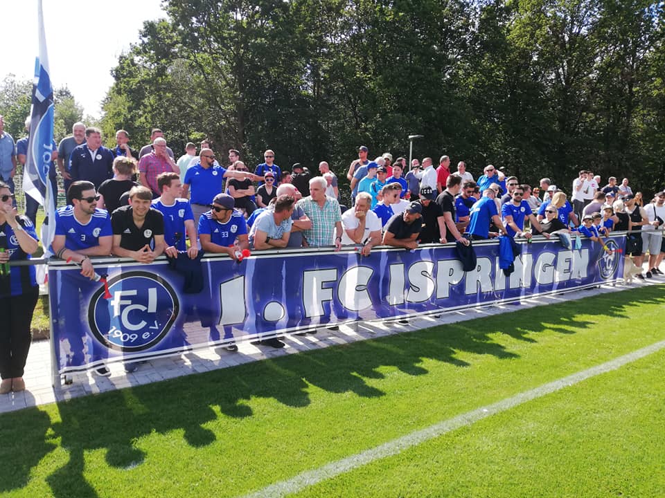 Mehrere Personen posieren vor einem großen Banner und zeigen Freude.