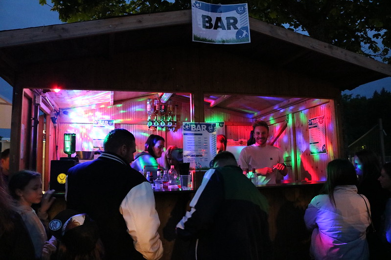 Menschen versammeln sich abends um eine Bar, lachen und genießen die Atmosphäre.